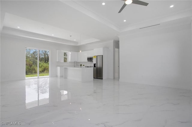 unfurnished living room with ceiling fan, a raised ceiling, and crown molding