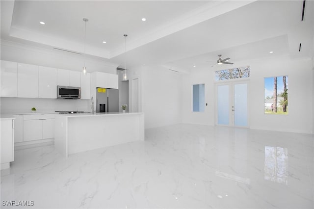 kitchen featuring a tray ceiling, white cabinetry, hanging light fixtures, and appliances with stainless steel finishes