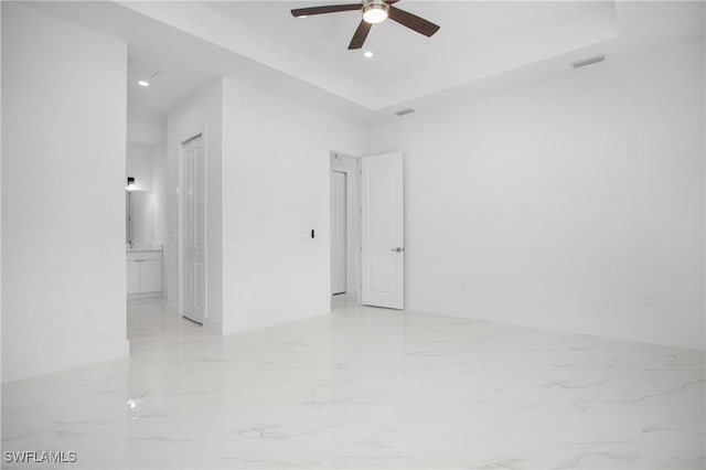 empty room featuring ceiling fan and a tray ceiling