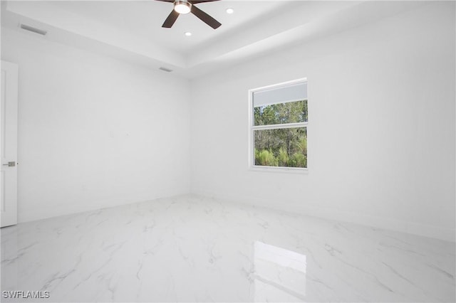 unfurnished room featuring ceiling fan and a tray ceiling