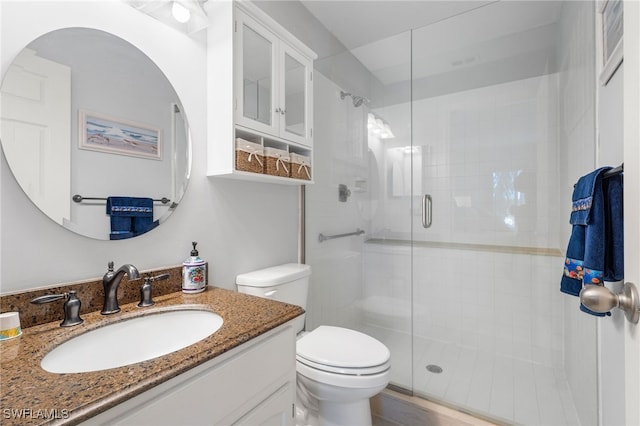 bathroom featuring vanity, toilet, and a shower with shower door