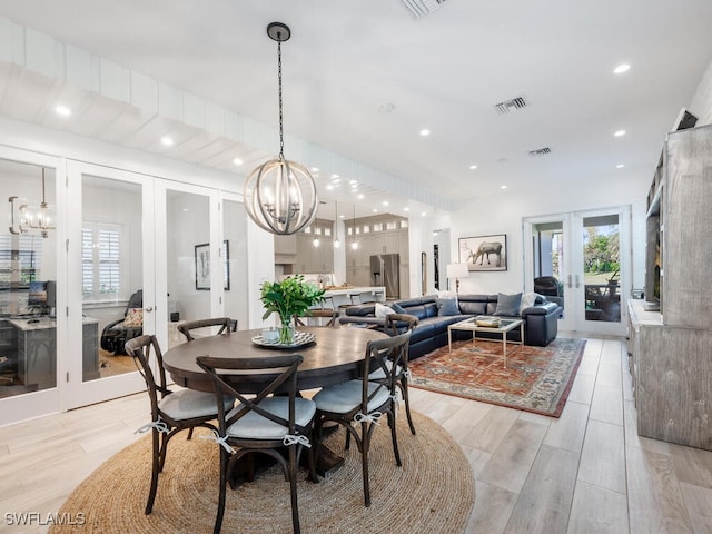 dining area with a notable chandelier, light wood-type flooring, and french doors