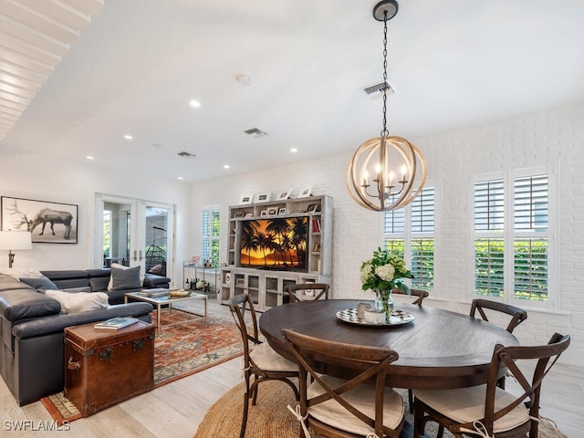 dining area featuring french doors, brick wall, and light hardwood / wood-style flooring