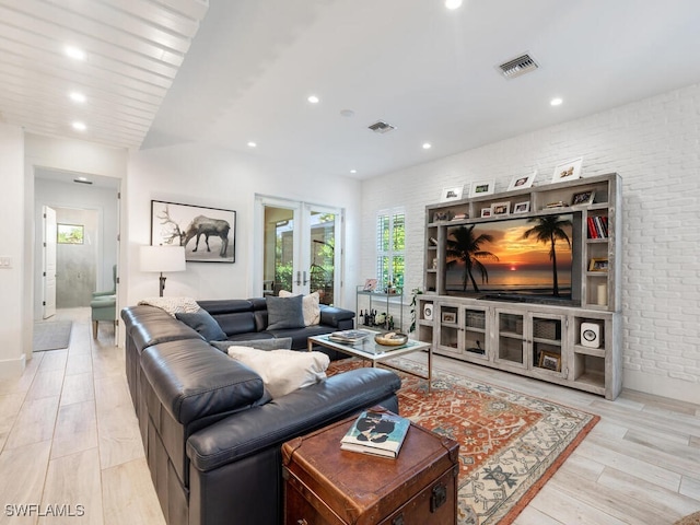 living room featuring light hardwood / wood-style floors, french doors, and brick wall