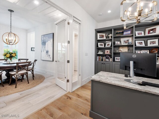 office area with light wood-type flooring and an inviting chandelier