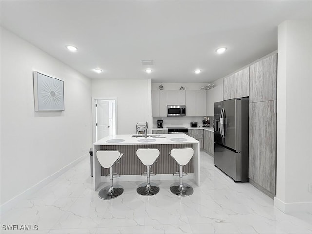 kitchen featuring a kitchen breakfast bar, a kitchen island with sink, sink, and stainless steel appliances