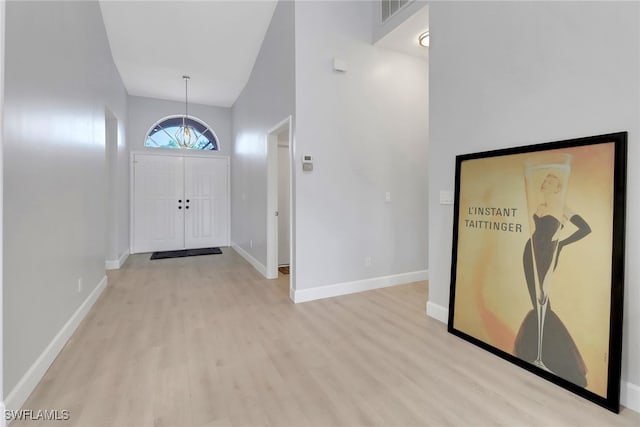 foyer entrance with light hardwood / wood-style flooring and high vaulted ceiling