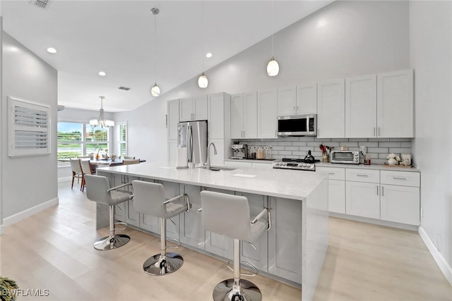 kitchen featuring hanging light fixtures, white cabinetry, a center island with sink, and stainless steel appliances