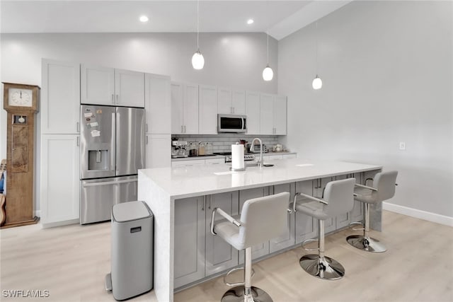 kitchen featuring appliances with stainless steel finishes, tasteful backsplash, sink, a center island with sink, and hanging light fixtures