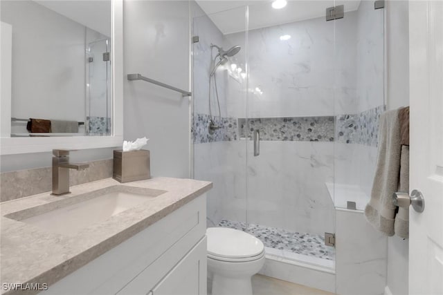 bathroom featuring vanity, toilet, and a shower with shower door