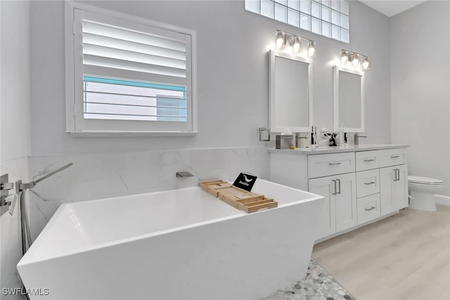 bathroom featuring wood-type flooring, vanity, toilet, and a tub