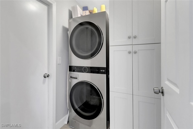 washroom with cabinets and stacked washing maching and dryer