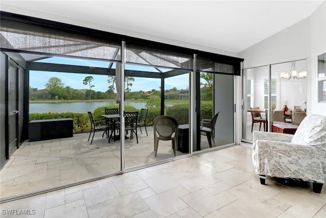 entryway featuring a chandelier, a water view, vaulted ceiling, and plenty of natural light