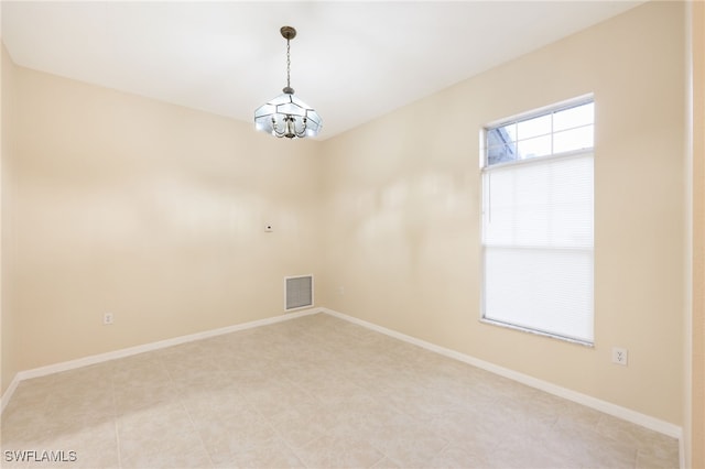 spare room featuring an inviting chandelier