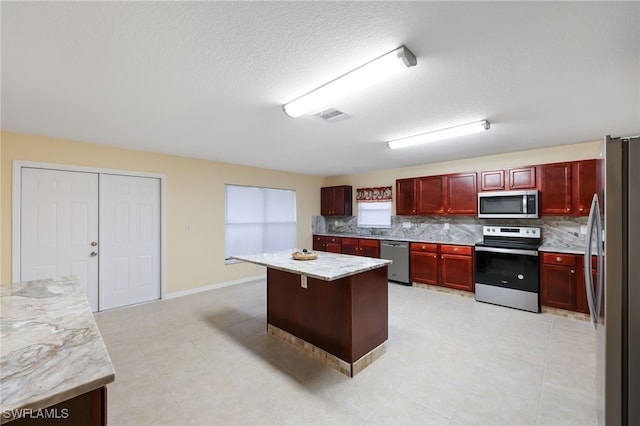 kitchen featuring a center island, a breakfast bar area, decorative backsplash, light stone countertops, and stainless steel appliances