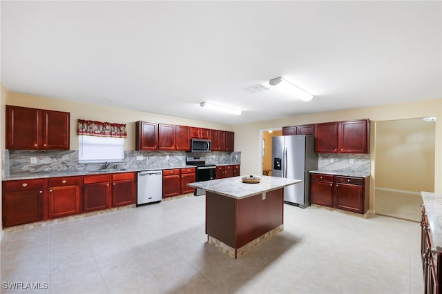 kitchen featuring light stone counters, a kitchen island, sink, and stainless steel appliances