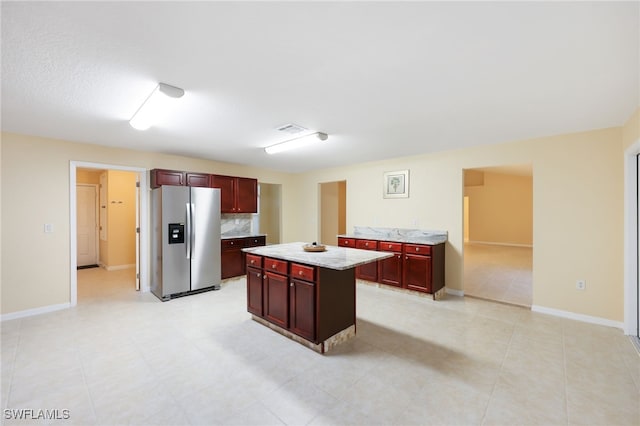 kitchen featuring tasteful backsplash, stainless steel fridge, a center island, and light tile patterned flooring