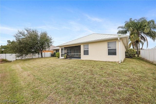 rear view of property featuring a lawn and a sunroom