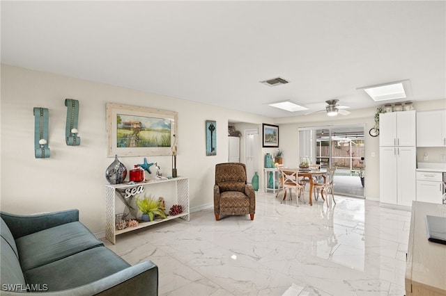 living room with ceiling fan and a skylight