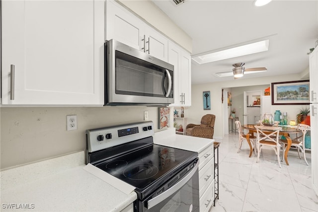 kitchen featuring ceiling fan, stainless steel appliances, and white cabinetry