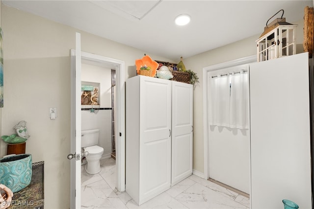 bathroom with toilet and tile walls