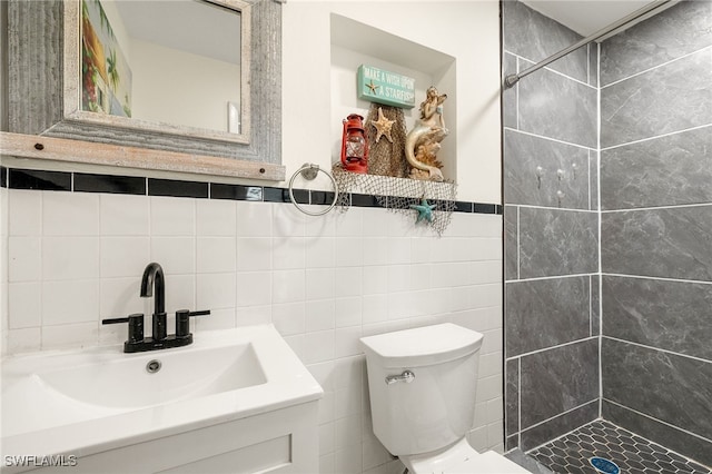 bathroom with sink, tile walls, toilet, and a tile shower