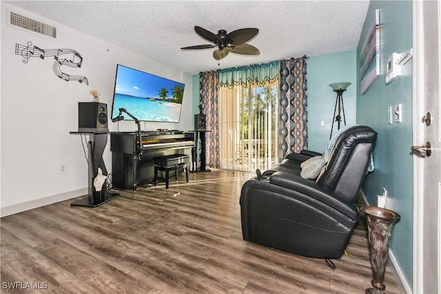 living area featuring hardwood / wood-style floors, ceiling fan, and a textured ceiling