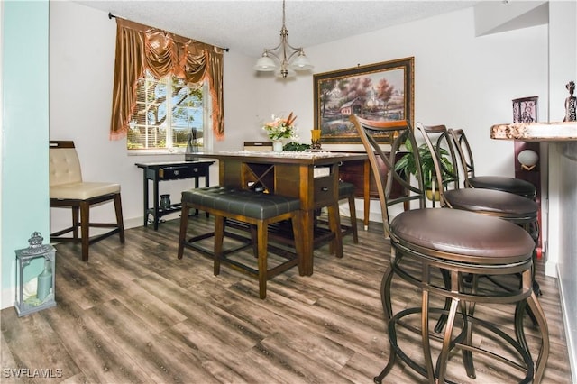 dining room with a textured ceiling, hardwood / wood-style flooring, and an inviting chandelier