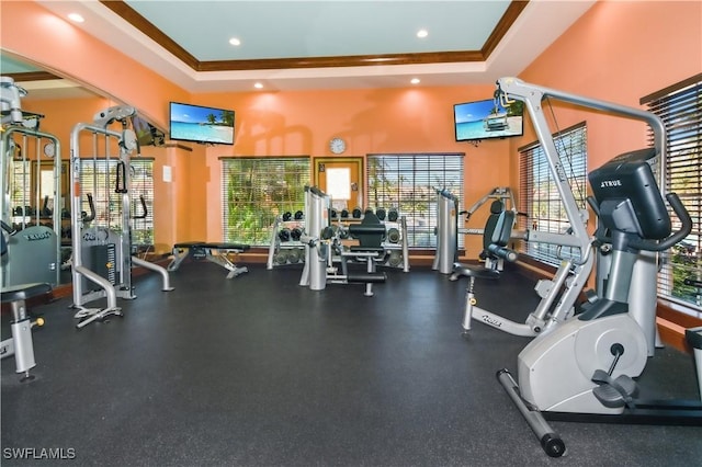 gym featuring a towering ceiling, a tray ceiling, and crown molding