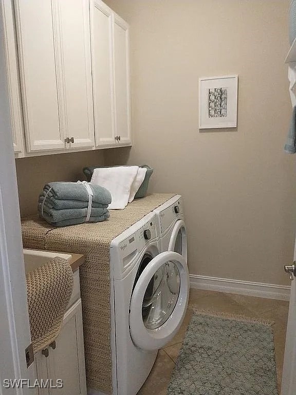 washroom featuring cabinets, light tile patterned floors, and washing machine and clothes dryer