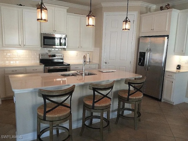 kitchen with white cabinets, a center island with sink, appliances with stainless steel finishes, and tasteful backsplash