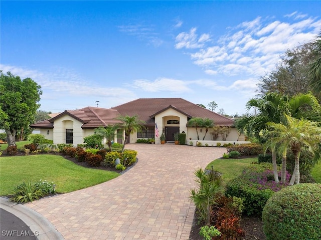 mediterranean / spanish house featuring a front yard and a garage