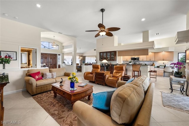 living room featuring ceiling fan with notable chandelier, light tile patterned floors, and high vaulted ceiling