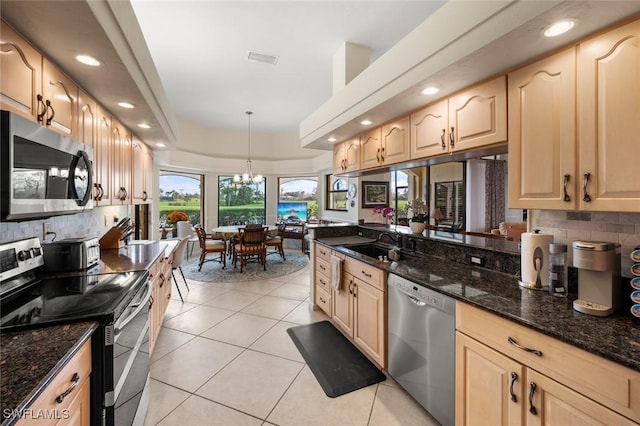 kitchen featuring pendant lighting, light brown cabinets, stainless steel appliances, dark stone countertops, and light tile patterned floors