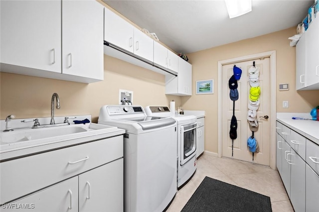 clothes washing area featuring washer and clothes dryer, sink, light tile patterned floors, and cabinets