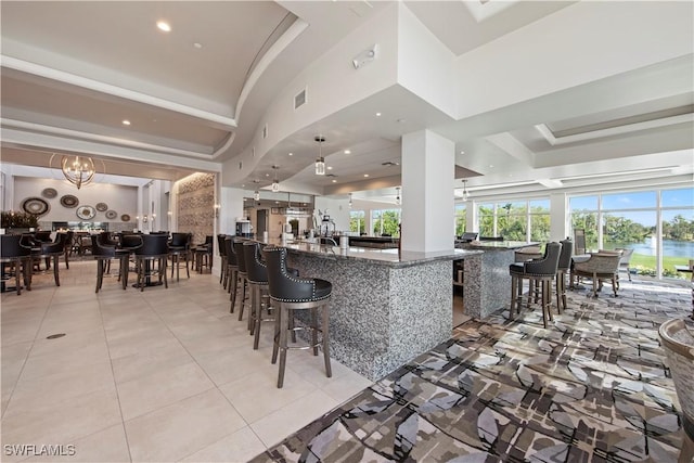 kitchen with decorative light fixtures, a raised ceiling, light tile patterned flooring, an inviting chandelier, and dark stone counters