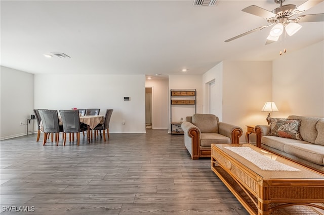 living room featuring ceiling fan and dark wood-type flooring