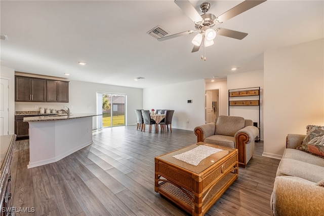 living room featuring hardwood / wood-style flooring, ceiling fan, and sink