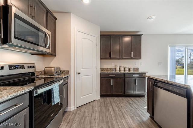 kitchen featuring light stone countertops, appliances with stainless steel finishes, light hardwood / wood-style flooring, and dark brown cabinets