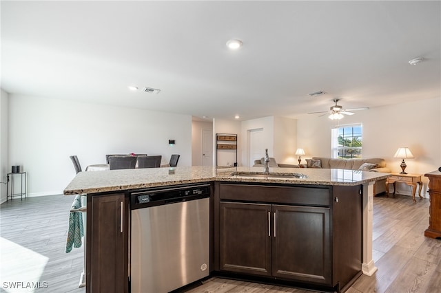 kitchen with stainless steel dishwasher, dark brown cabinets, sink, and an island with sink