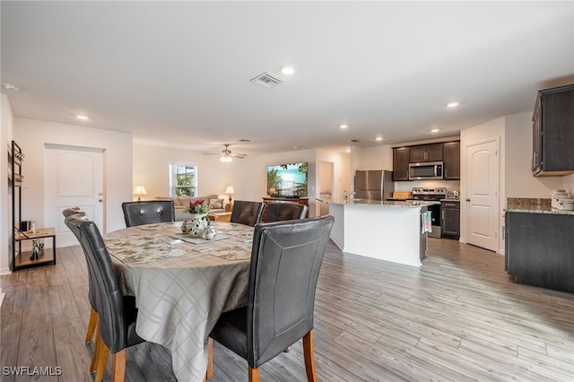 dining room featuring light wood-type flooring, ceiling fan, and sink