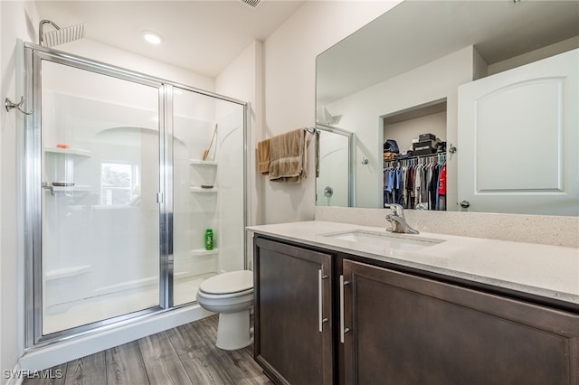 bathroom featuring toilet, vanity, a shower with shower door, and hardwood / wood-style flooring