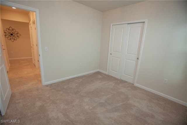 unfurnished bedroom with light colored carpet and a closet