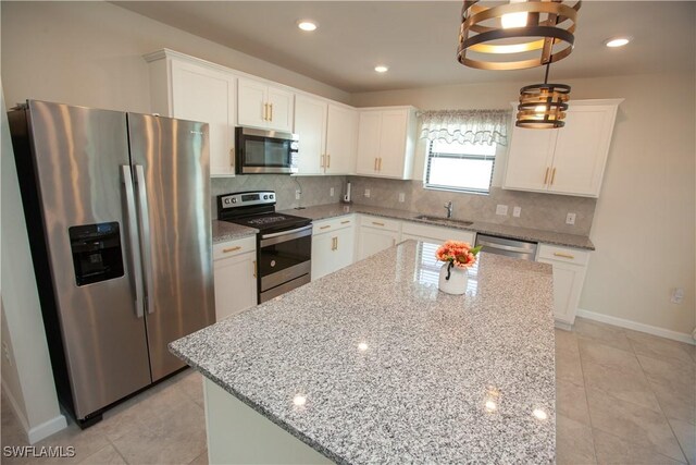 kitchen with white cabinets, a kitchen island, stainless steel appliances, and pendant lighting