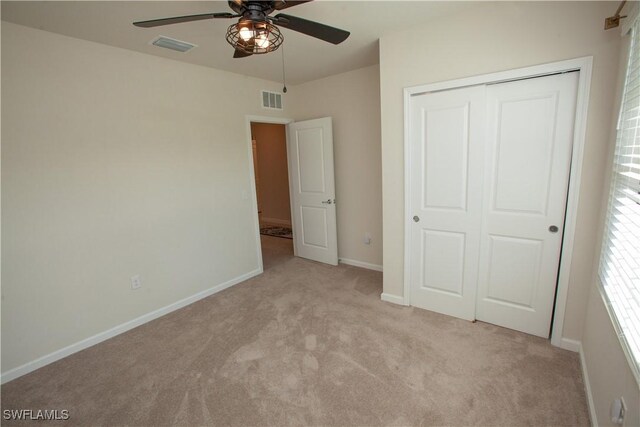 unfurnished bedroom with ceiling fan, a closet, and light carpet