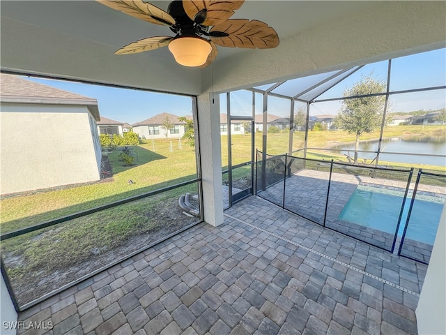 unfurnished sunroom featuring ceiling fan and a water view