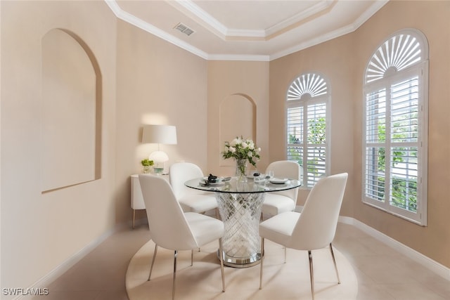 tiled dining space featuring a raised ceiling and crown molding