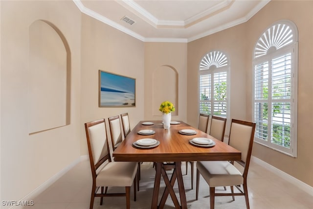 dining space with light tile patterned flooring, ornamental molding, and a raised ceiling