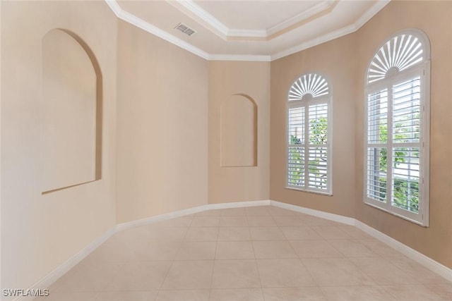 tiled spare room featuring crown molding and a tray ceiling