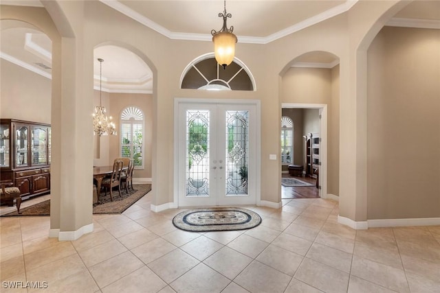 entrance foyer featuring light tile patterned floors, crown molding, a chandelier, and french doors